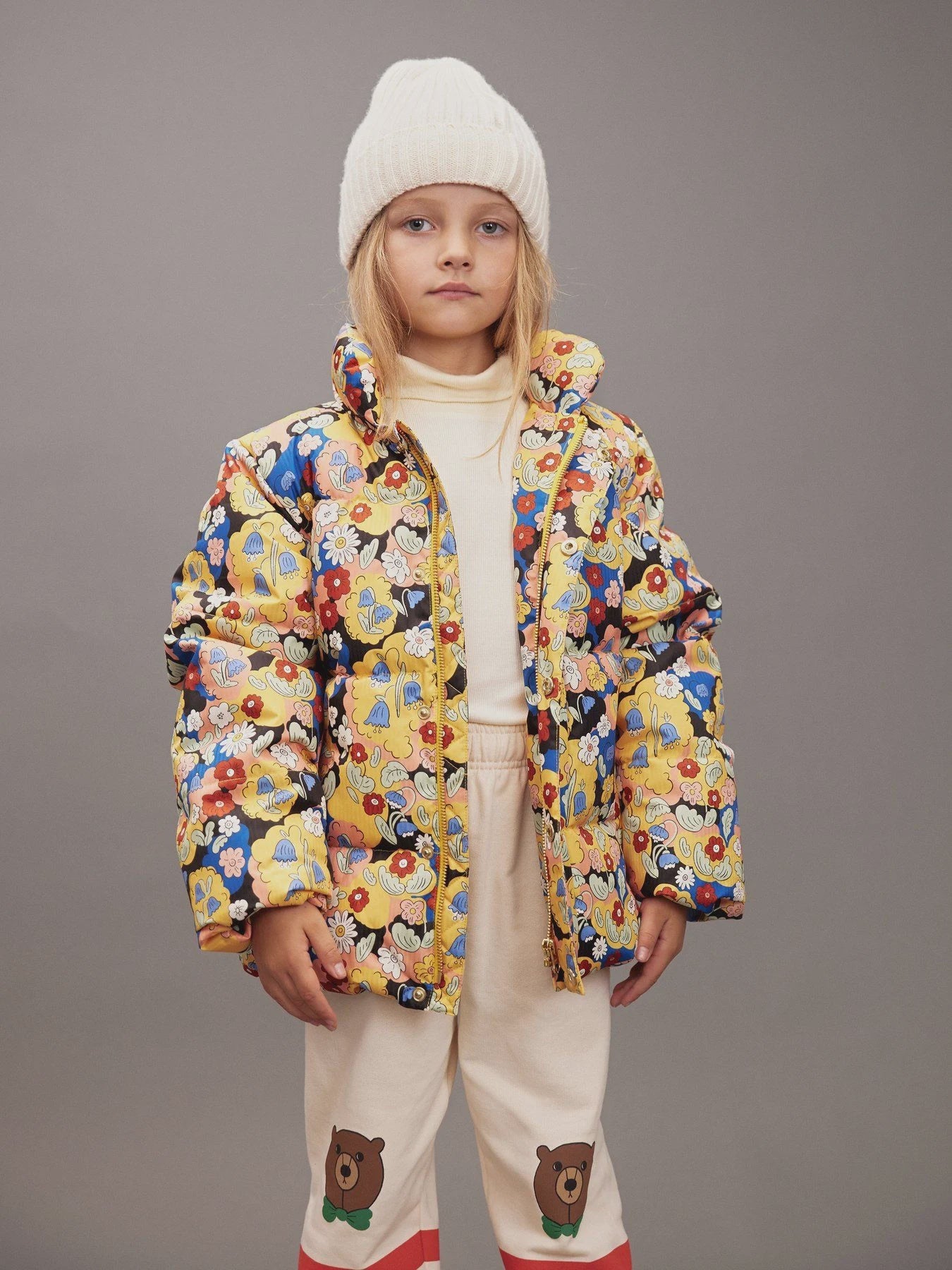 child wearing multi color coat in front of gray background